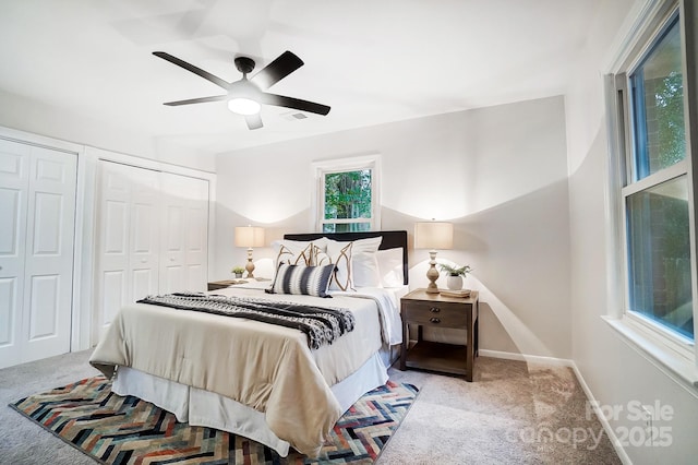 carpeted bedroom with two closets and ceiling fan