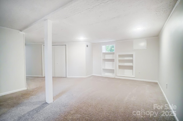 basement featuring light colored carpet and a textured ceiling