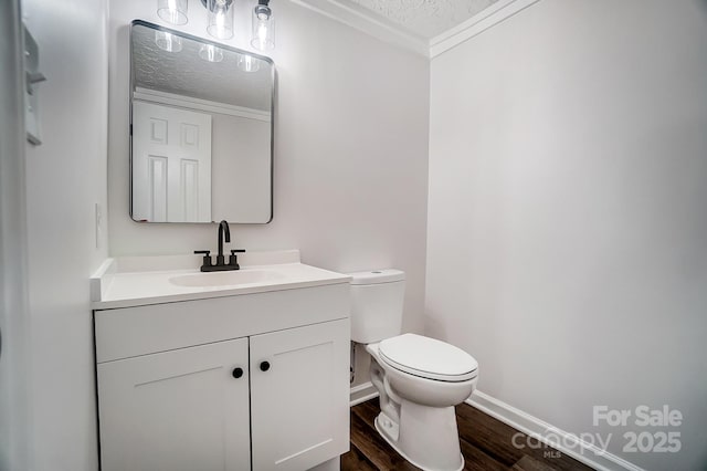 bathroom featuring crown molding, vanity, wood-type flooring, a textured ceiling, and toilet