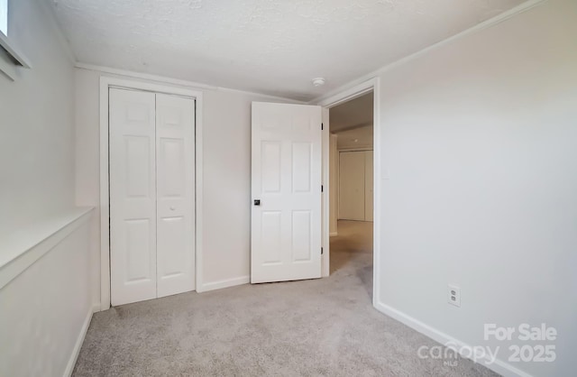 unfurnished bedroom featuring light colored carpet, a closet, and a textured ceiling