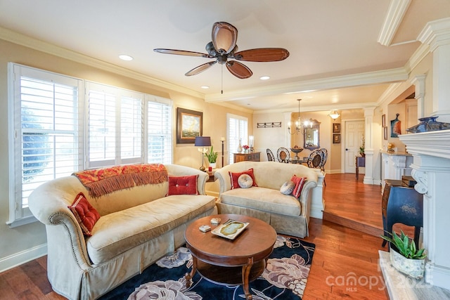 living room featuring hardwood / wood-style flooring, crown molding, ceiling fan with notable chandelier, and ornate columns