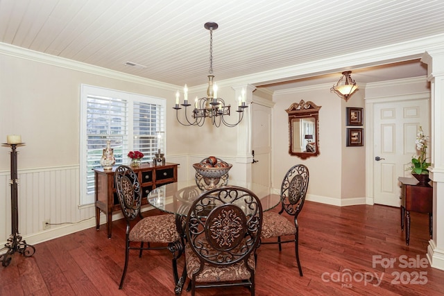 dining space with ornate columns, crown molding, dark hardwood / wood-style floors, and an inviting chandelier