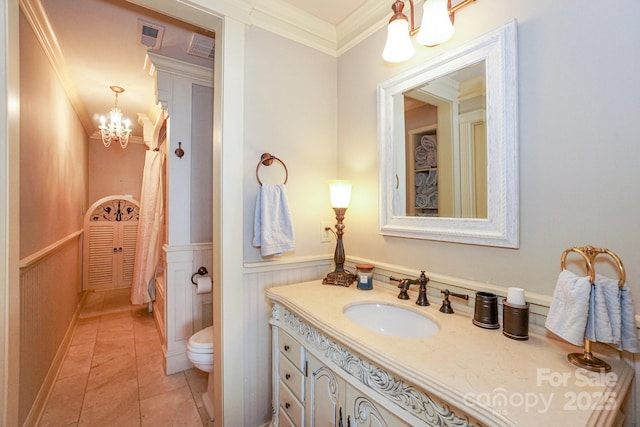 bathroom with tile patterned floors, toilet, ornamental molding, vanity, and a notable chandelier