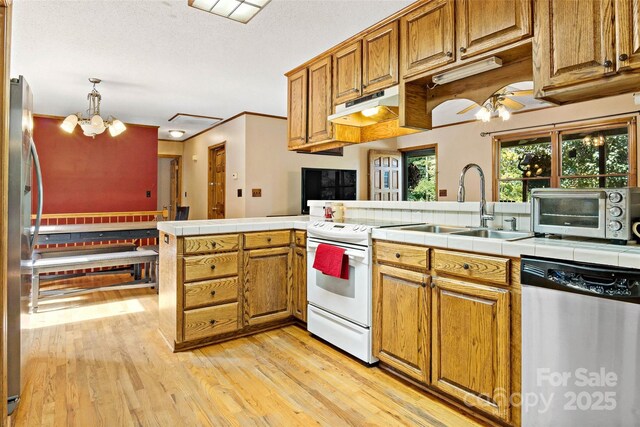 kitchen with a toaster, under cabinet range hood, stainless steel appliances, light wood-style floors, and brown cabinets