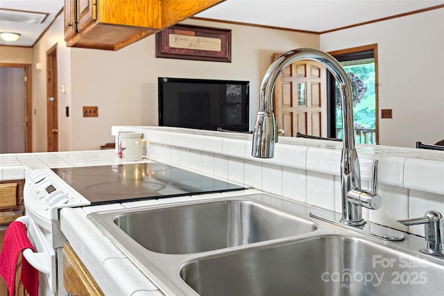 kitchen featuring tile countertops, a sink, and crown molding