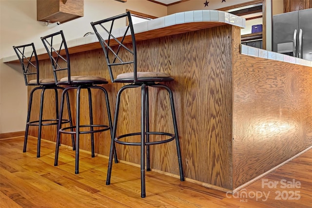 details with baseboards, wood finished floors, and stainless steel fridge with ice dispenser