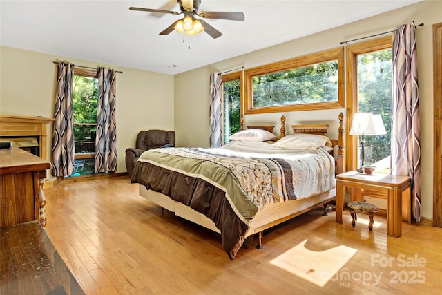 bedroom featuring a ceiling fan, a fireplace, and hardwood / wood-style flooring
