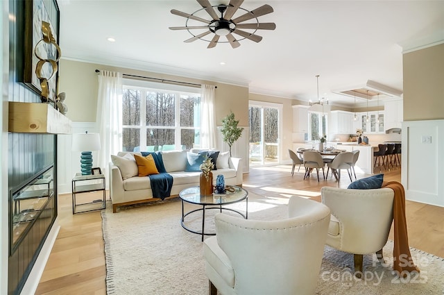 living room with a wealth of natural light, ornamental molding, light hardwood / wood-style floors, and ceiling fan