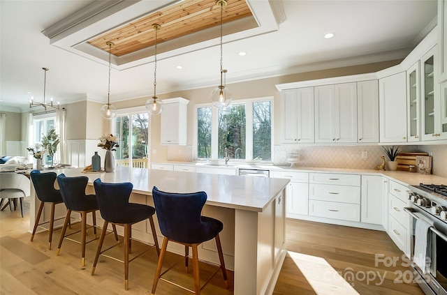 kitchen featuring a kitchen island, appliances with stainless steel finishes, decorative light fixtures, a breakfast bar area, and white cabinets