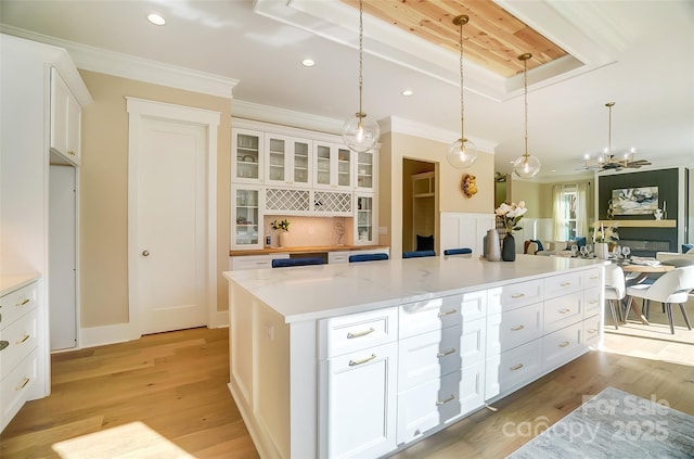 kitchen featuring hanging light fixtures, ornamental molding, a center island, and white cabinets