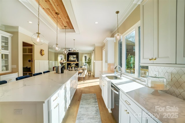 kitchen featuring stainless steel dishwasher, decorative light fixtures, a kitchen island, and white cabinets