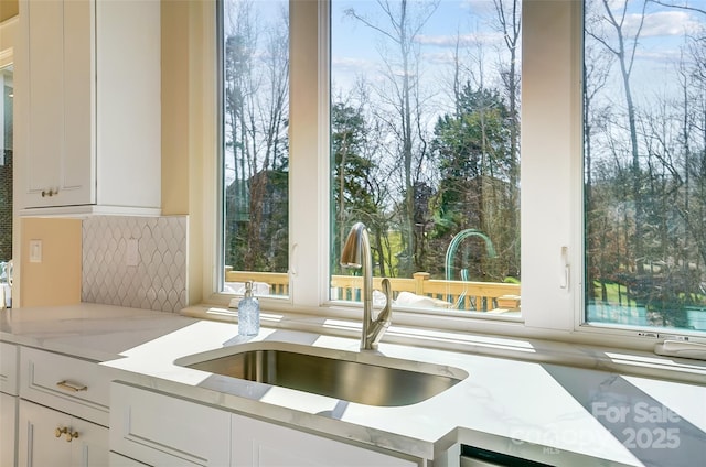 details featuring light stone countertops, sink, decorative backsplash, and white cabinets