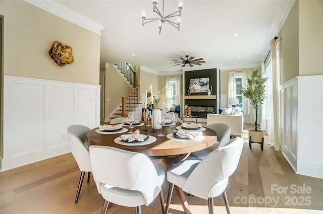 dining space with crown molding, a fireplace, light hardwood / wood-style flooring, and a wealth of natural light