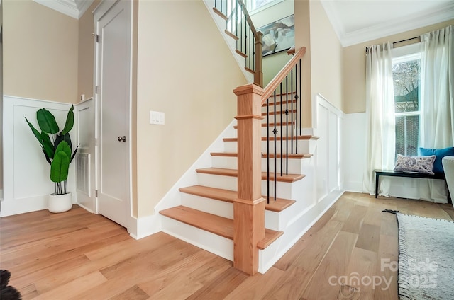 stairs with wood-type flooring and ornamental molding