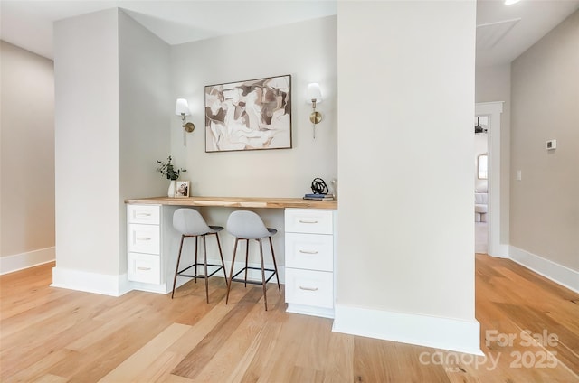 office featuring built in desk and light hardwood / wood-style floors