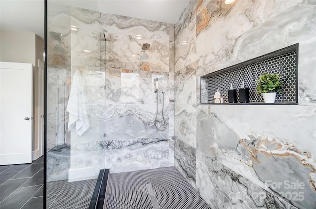 bathroom featuring tiled shower and tile patterned flooring