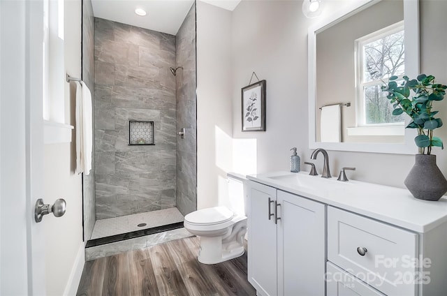 bathroom with vanity, hardwood / wood-style floors, toilet, and a tile shower