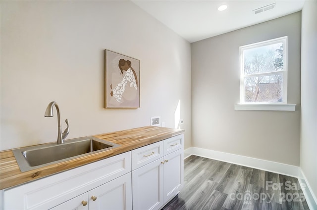 interior space featuring butcher block counters, sink, dark hardwood / wood-style floors, and white cabinets