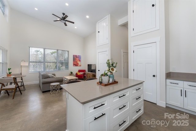 kitchen with white cabinets, a center island, high vaulted ceiling, and ceiling fan