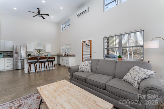 living room with ceiling fan, sink, a wall mounted AC, and a high ceiling