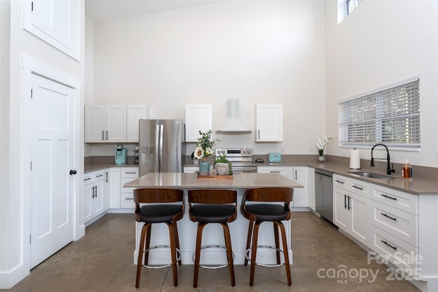 kitchen with stainless steel appliances, custom range hood, white cabinets, a kitchen island, and sink