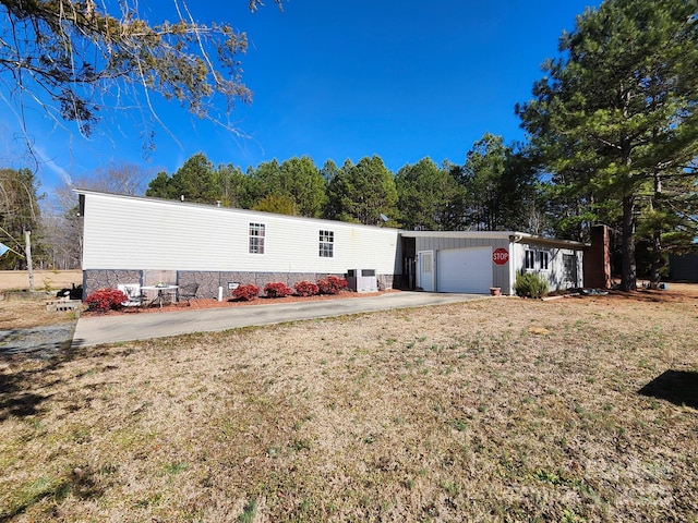 manufactured / mobile home featuring a garage, central air condition unit, and a front lawn