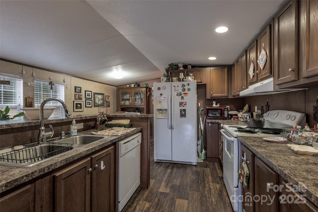 kitchen featuring lofted ceiling, sink, dark stone countertops, dark hardwood / wood-style flooring, and white appliances