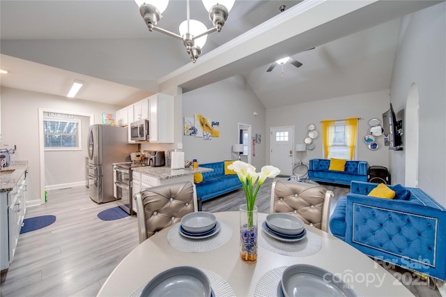 dining area featuring lofted ceiling, sink, ceiling fan with notable chandelier, and light hardwood / wood-style floors