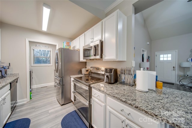 kitchen with appliances with stainless steel finishes, white cabinets, and light stone counters