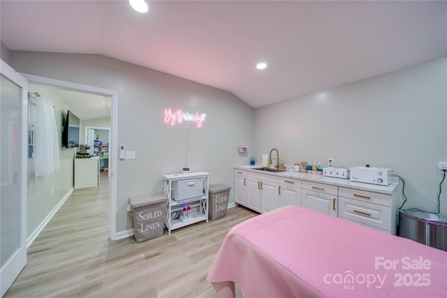 bedroom featuring lofted ceiling, sink, and light hardwood / wood-style flooring