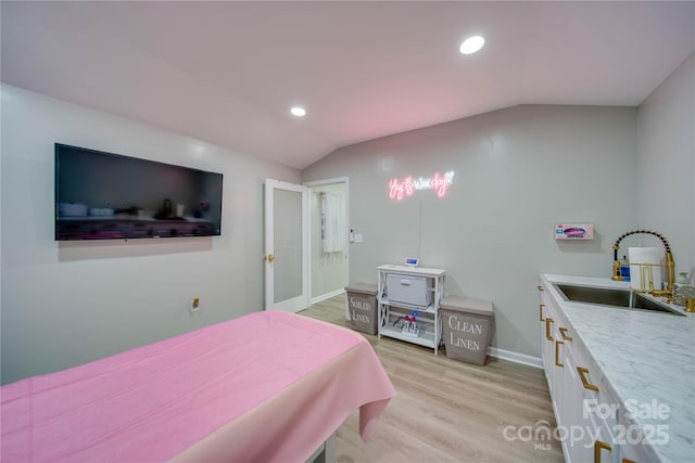 bedroom with lofted ceiling, sink, and light hardwood / wood-style flooring