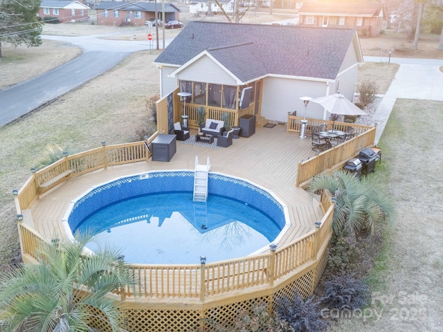 view of pool with an outdoor hangout area, a deck, and a sunroom