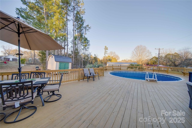 wooden terrace with a fenced in pool and a storage unit