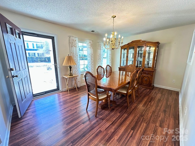 dining space with a textured ceiling, a notable chandelier, visible vents, baseboards, and dark wood-style floors