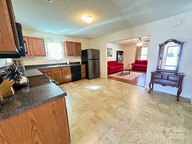 kitchen featuring dark countertops, black appliances, open floor plan, and a wealth of natural light