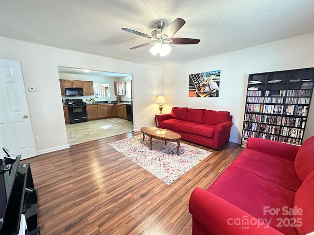 living room featuring a ceiling fan, dark wood finished floors, a textured ceiling, and baseboards