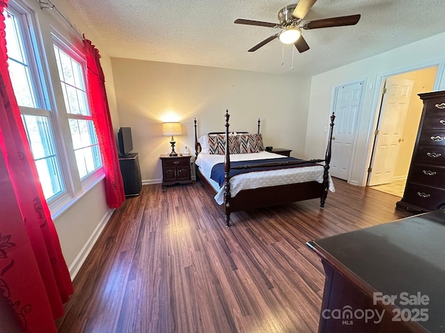 bedroom with a textured ceiling, dark wood-type flooring, a ceiling fan, and baseboards