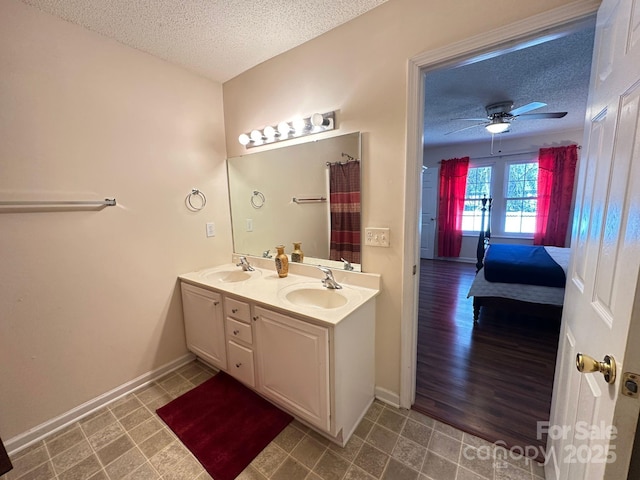 bathroom featuring double vanity, a textured ceiling, connected bathroom, and a sink