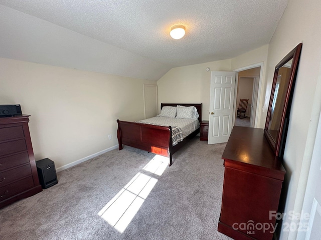 bedroom featuring light carpet, a textured ceiling, lofted ceiling, and baseboards