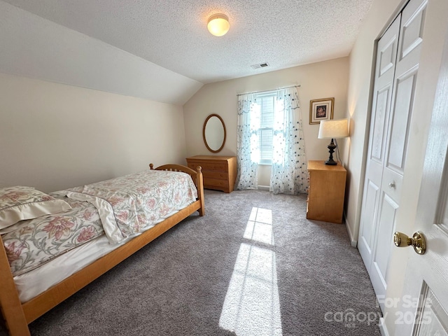 bedroom featuring lofted ceiling, a textured ceiling, carpet flooring, visible vents, and a closet