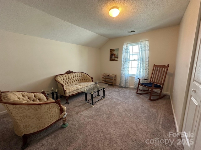 living area with a textured ceiling, visible vents, baseboards, vaulted ceiling, and carpet