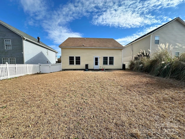 rear view of property with fence and a lawn