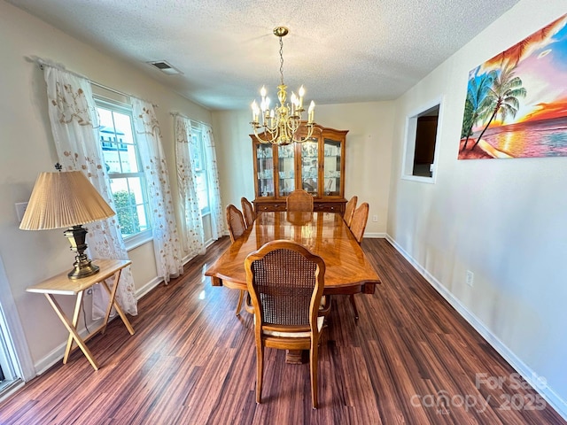 dining area with a chandelier, dark wood finished floors, a textured ceiling, and baseboards