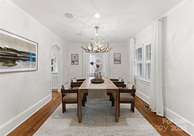 2809 Glendale Rd, Charlotte, NC 28209 - dining area featuring a chandelier, arched walkways, ornamental molding, wood finished floors, and baseboards