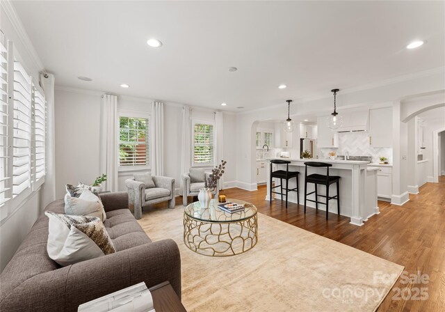 2809 Glendale Rd, Charlotte, NC 28209 - living area with arched walkways, light wood-type flooring, ornamental molding, recessed lighting, and baseboards