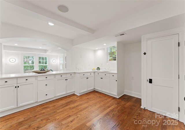2809 Glendale Rd, Charlotte, NC 28209 - kitchen with light wood-style floors, arched walkways, light countertops, white cabinetry, and recessed lighting