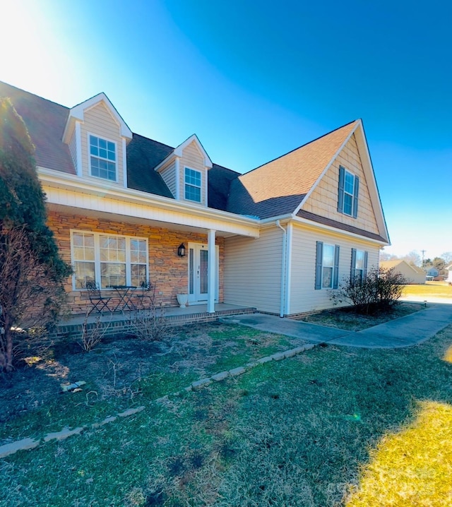 cape cod home with a front yard and covered porch