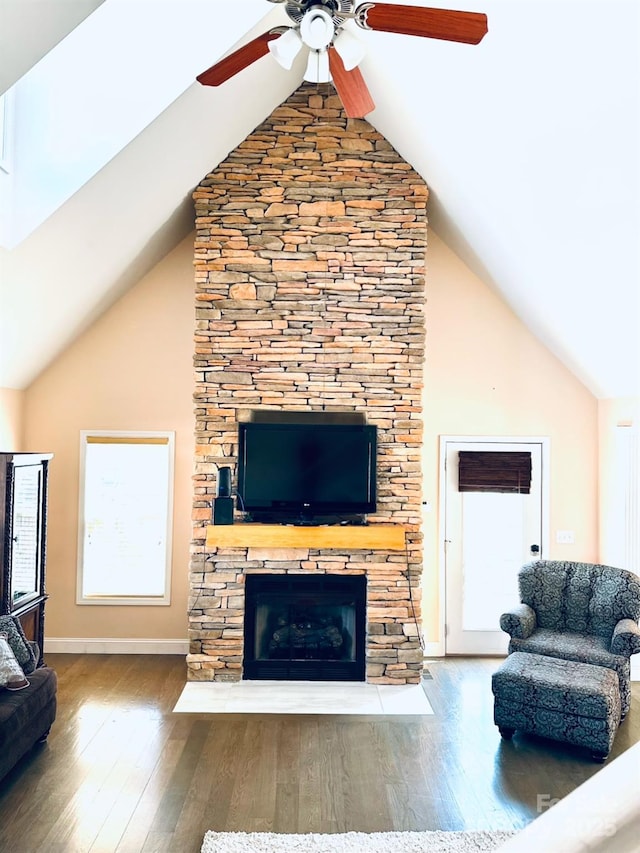 living room with hardwood / wood-style flooring, a stone fireplace, high vaulted ceiling, and ceiling fan