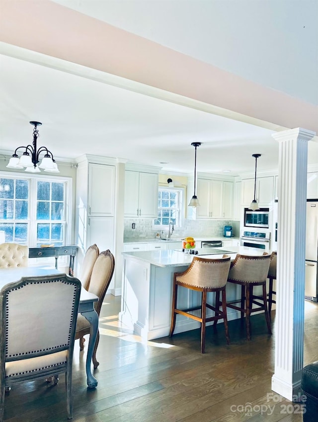 kitchen with decorative light fixtures, stainless steel appliances, decorative backsplash, and white cabinets