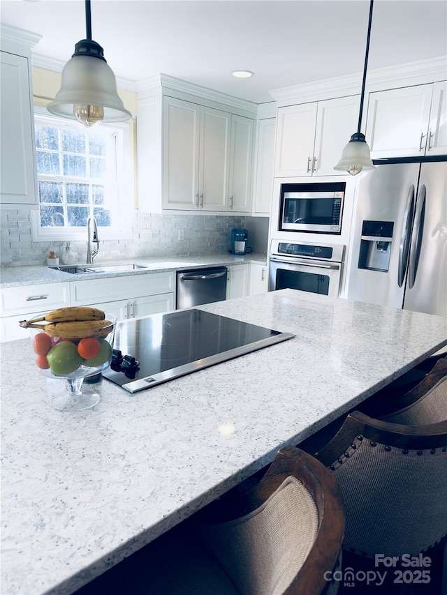 kitchen with stainless steel appliances, sink, pendant lighting, and light stone counters